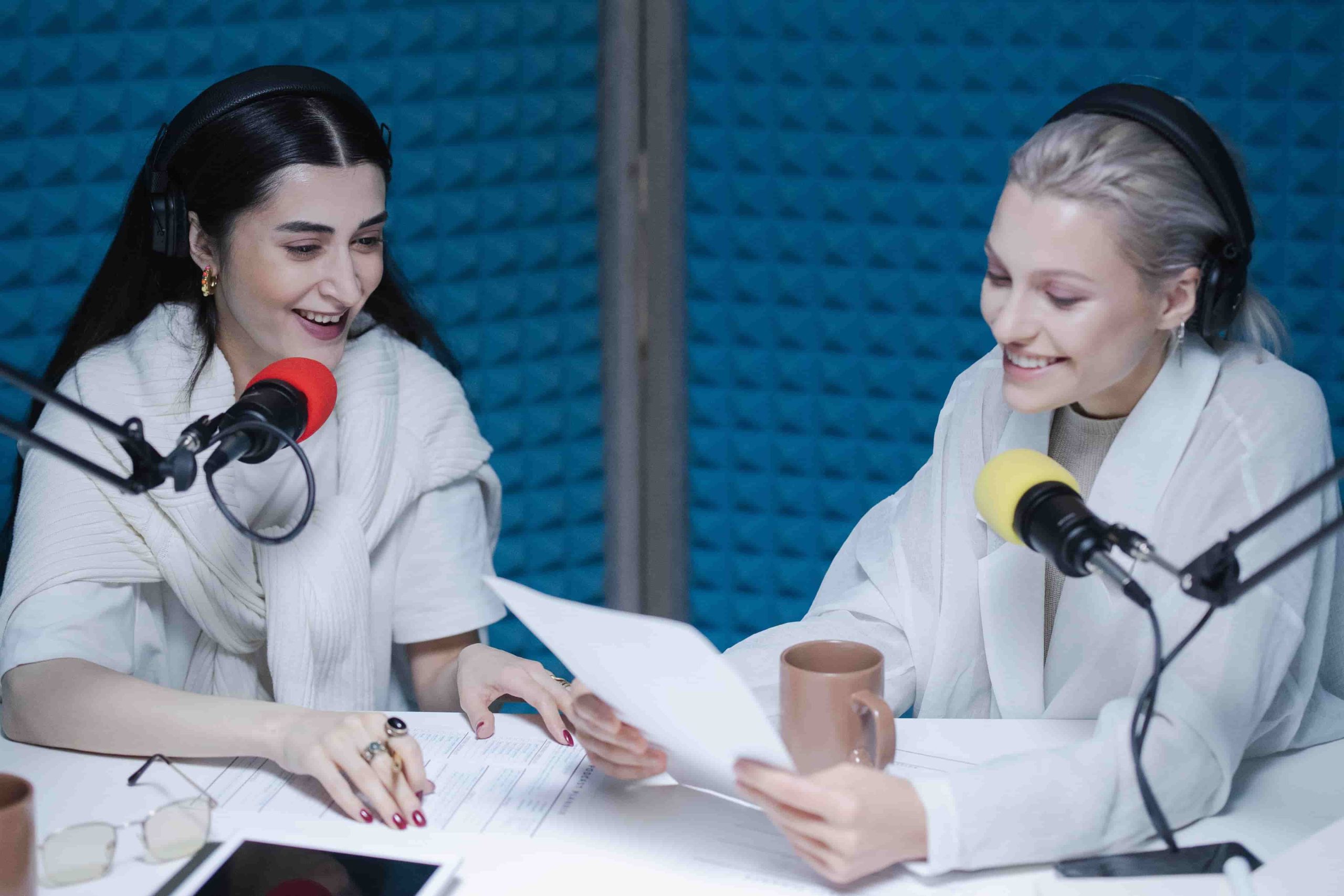 Bild von 2 Frauen bei der Podcast Aufnahme im Podcast-Studio. Sie besprechen die Podcast Shownotes.